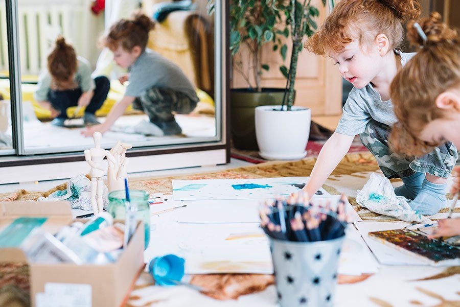 Pupils painting and creating art together on the classroom floor